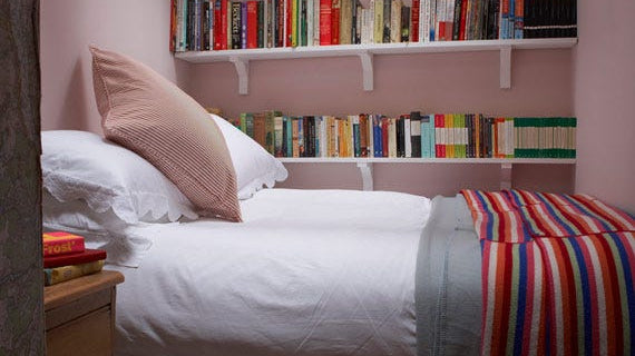 Cosy bedroom with bookshelves painted in Farrow & Ball Calamine