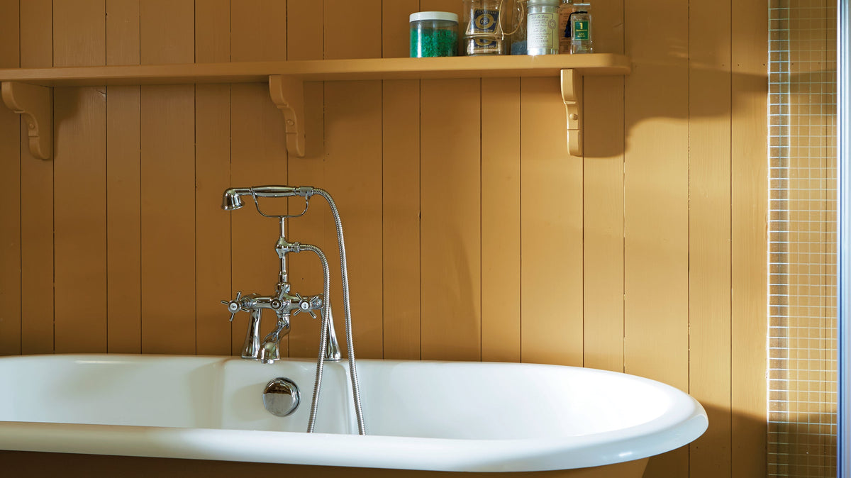 Bathroom with panelling and roll top bath painted in Farrow & Ball India Yellow